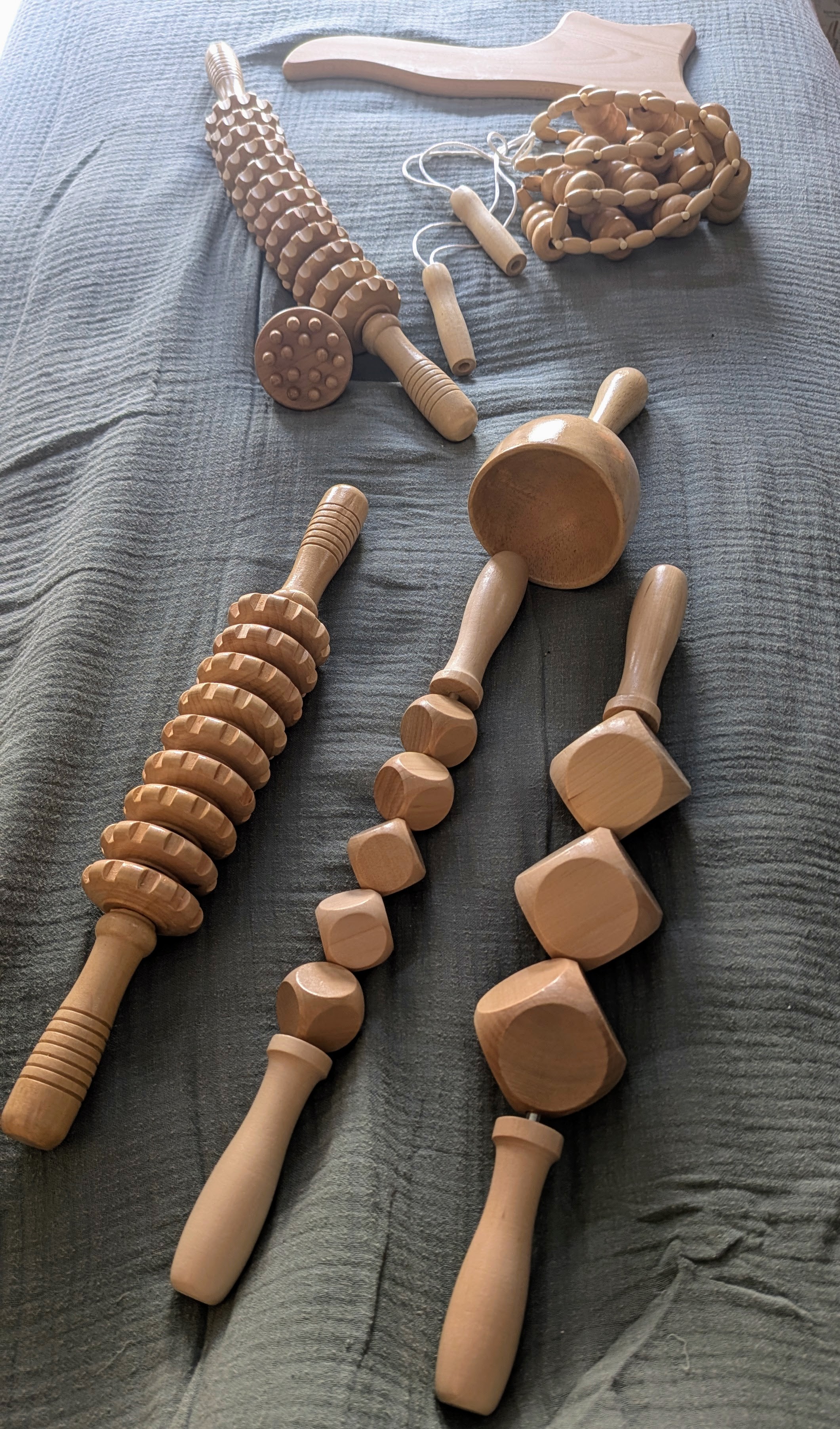 Colombian wood therapy tools laid out on massage table covered in textured cotton sheet